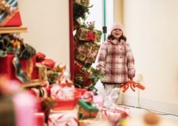 A little girl smiles as she looks into a room filled with gifts at Camp Christmas