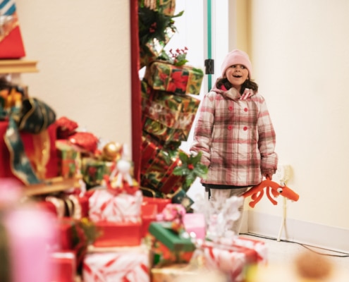 A little girl smiles as she looks into a room filled with gifts at Camp Christmas