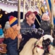 A man shouts with joy with his children as they ride the carousel at Camp Christmas