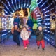 A group of children run through a lighted archway at Camp Christmas