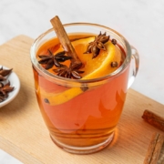 A glass of wassail decorated with spices