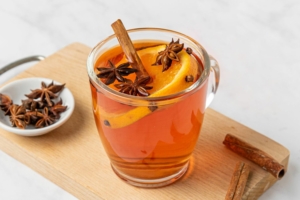 A glass of wassail decorated with spices