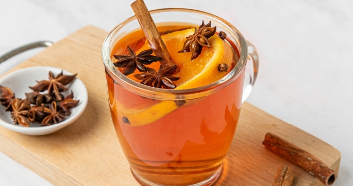 A glass of wassail decorated with spices