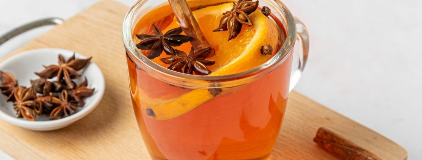 A glass of wassail decorated with spices