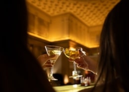 A couple clinks together their cocktail glasses at range restaurant
