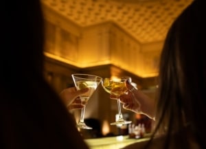 A couple clinks together their cocktail glasses at range restaurant