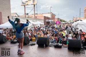 A woman performs in front of a large crowd at Juneteenth Music Festival