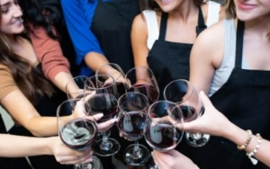 Women toast with wine glasses at a painting class