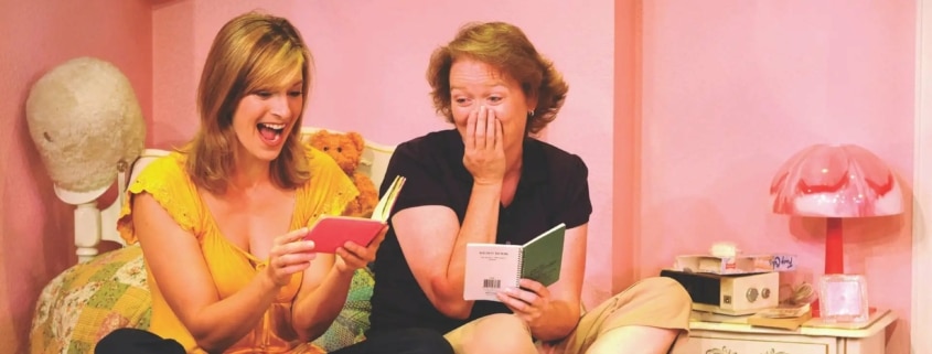 Linda Klein and Barbara Gehring sit on a bed reading their diaries in The Secret Comedy of Women