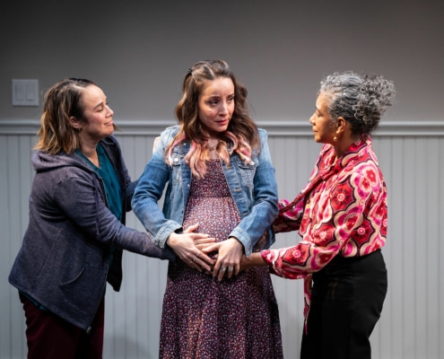 Celia and Tere stand on either side of Yolie, all with their hands on Yolie's pregnant belly.