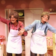 Linda Klein and Barbara Gehring dressed as older women show off their homemade crafts