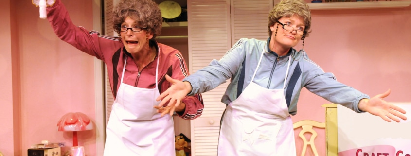 Linda Klein and Barbara Gehring dressed as older women show off their homemade crafts