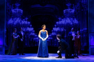 A glamorous Anya in a blue gown watches as Dmitri kneels in front of her