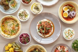 Several plates filled with Mediterranean food on a table at Safta