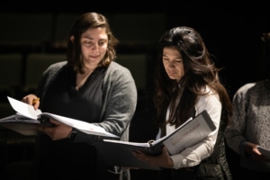 Zoe Golub Sass and Christina Pumariega stand close together while looking over the script for Joan Dark