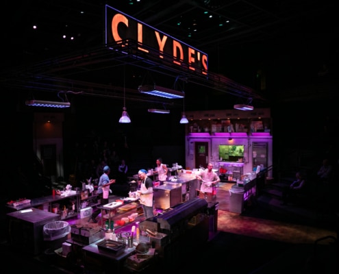 Clyde's glows in large lettering above the kitchen set. Four cooks are scattered about, prepping the kitchen.