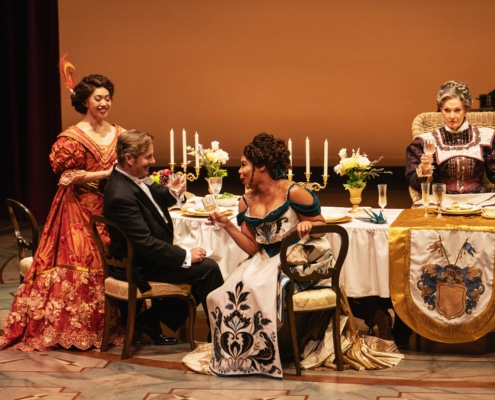 Sydney Chow, Edward Staudenmayer, Soara-Joy Ross, and Leslie Alexander cheers their champaign flutes around an elegant dinner table.