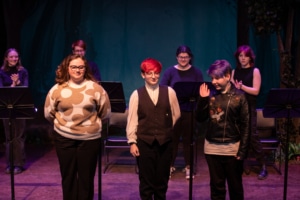 The three student playwrights stand onstage together