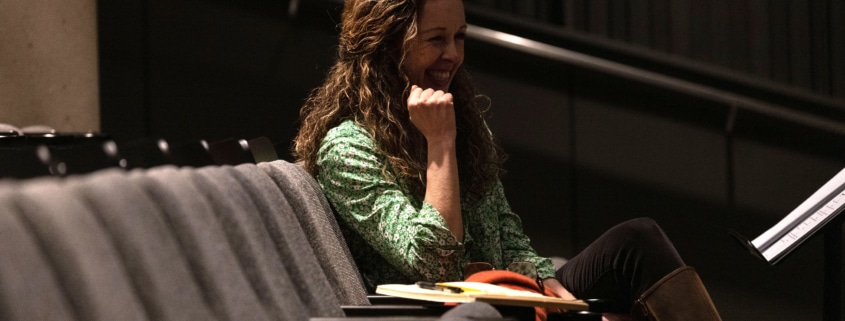 Playwright Kirsten Potter smiles while seated in the audience