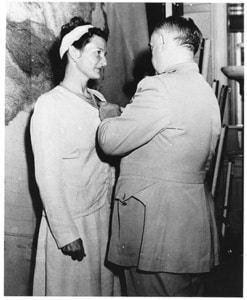 Virginia Hall awarded a medal for her services. A man stands pinning it to her dress.