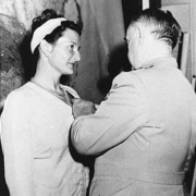 Virginia Hall awarded a medal for her services. A man stands pinning it to her dress.