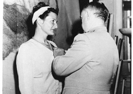 Virginia Hall awarded a medal for her services. A man stands pinning it to her dress.