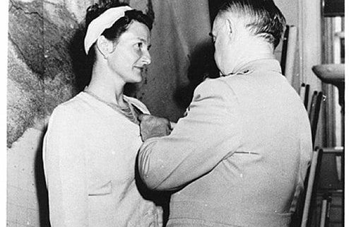 Virginia Hall awarded a medal for her services. A man stands pinning it to her dress.