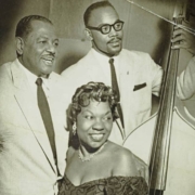 Charlotte Cowens sits at a piano with two other musicians