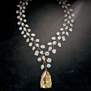 A yellow diamond pendant hangs from a diamond chain made to look like delicate leaves