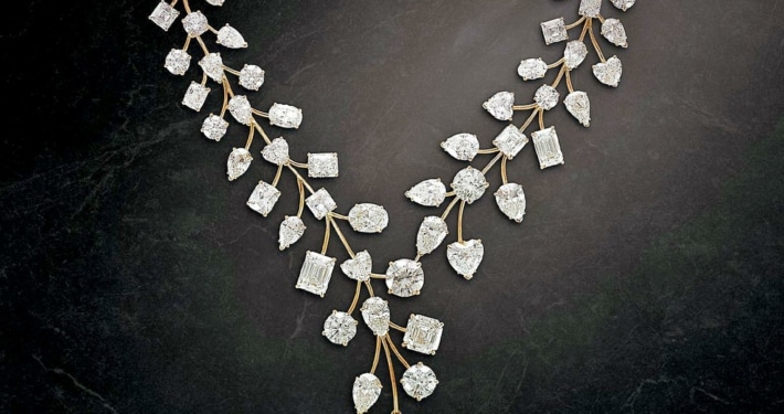 A yellow diamond pendant hangs from a diamond chain made to look like delicate leaves