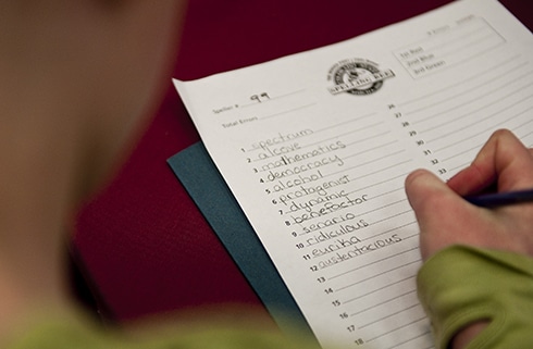 A child writes words on a worksheet at the Colorado State Spelling Bee