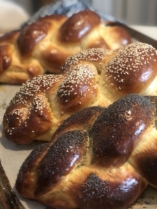 A close up of three loaves of baked challah