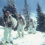 A line of soldiers snowshoe down a mountain in Camp Hale