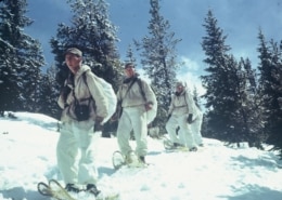 A line of soldiers snowshoe down a mountain in Camp Hale