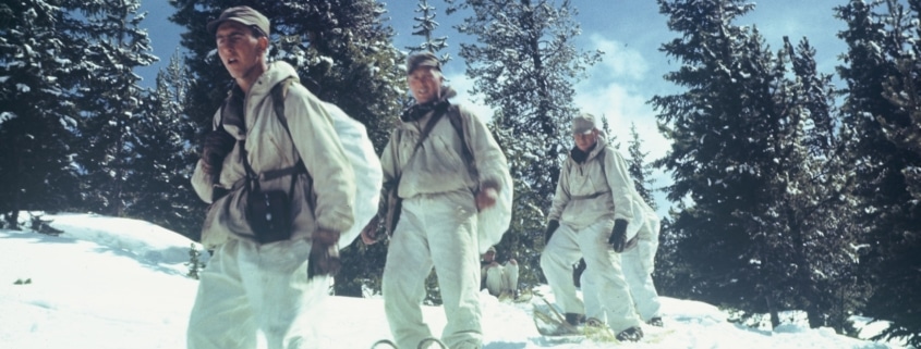 A line of soldiers snowshoe down a mountain in Camp Hale