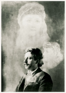 A portrait of J. Randall Brown, a ghostly figure of a woman hovers above him