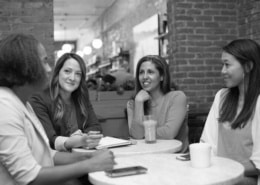 A group of women are seated at a table in discussion