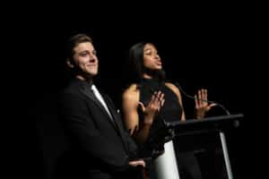 Thomas Beeker and Madison Manning, wearing black tie, present at a podium during the 2023 Bobby G Awards