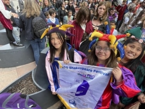 A group of students wearing costumes smile for a photo during the DPS Shakespeare Festival parade