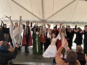 A large number of students clasp hands as they take a bow after performing in the DPS Shakespeare Festival