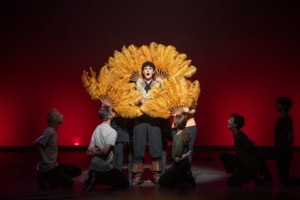 Ethan Hoover stands framed by classic, feathered fans while performing in Lakewood High School's production of Something Rotten during the Bobby G Awards