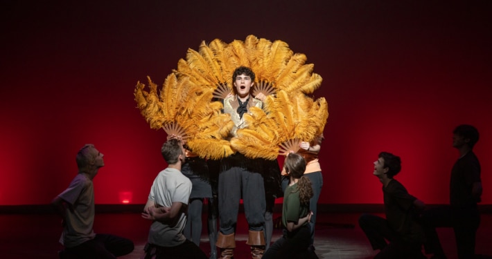 Ethan Hoover stands framed by classic, feathered fans while performing in Lakewood High School's production of Something Rotten during the Bobby G Awards