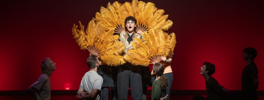 Ethan Hoover stands framed by classic, feathered fans while performing in Lakewood High School's production of Something Rotten during the Bobby G Awards