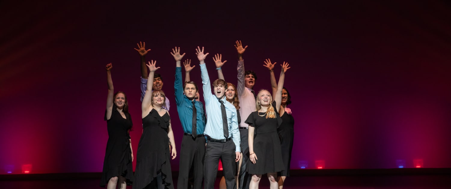 The Lead Performer nominees stand huddled together, singing the final note of the medley at the Bobby G Awards. Each has one arm raised, fingers reaching high.