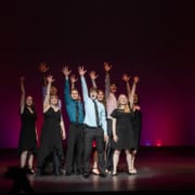 The Lead Performer nominees stand huddled together, singing the final note of the medley at the Bobby G Awards. Each has one arm raised, fingers reaching high.