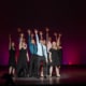 The Lead Performer nominees stand huddled together, singing the final note of the medley at the Bobby G Awards. Each has one arm raised, fingers reaching high.