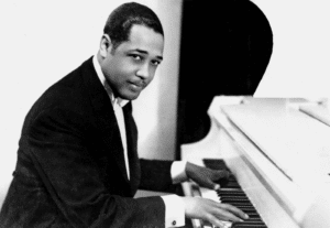 Duke Ellington plays the piano, looking at the camera