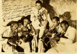 The Lucky Millinders pose for a photo with their instruments. The photo is autographed.