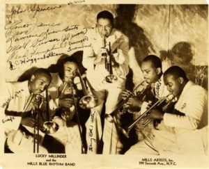 The Lucky Millinders pose for a photo with their instruments. The photo is autographed.