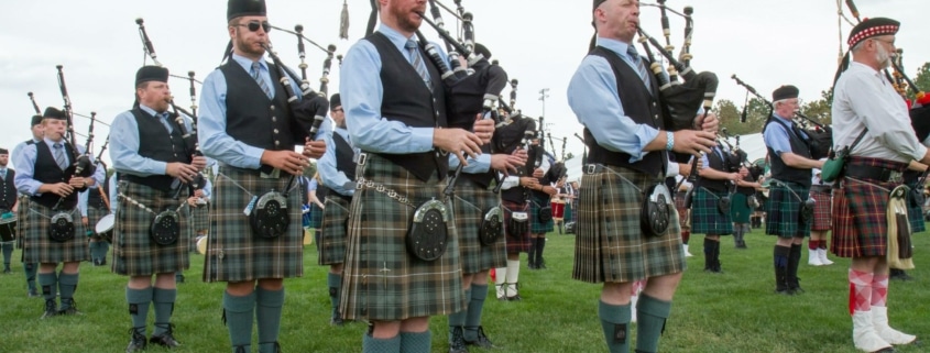 Rows of musicians playing the bagpipes wearing kilts